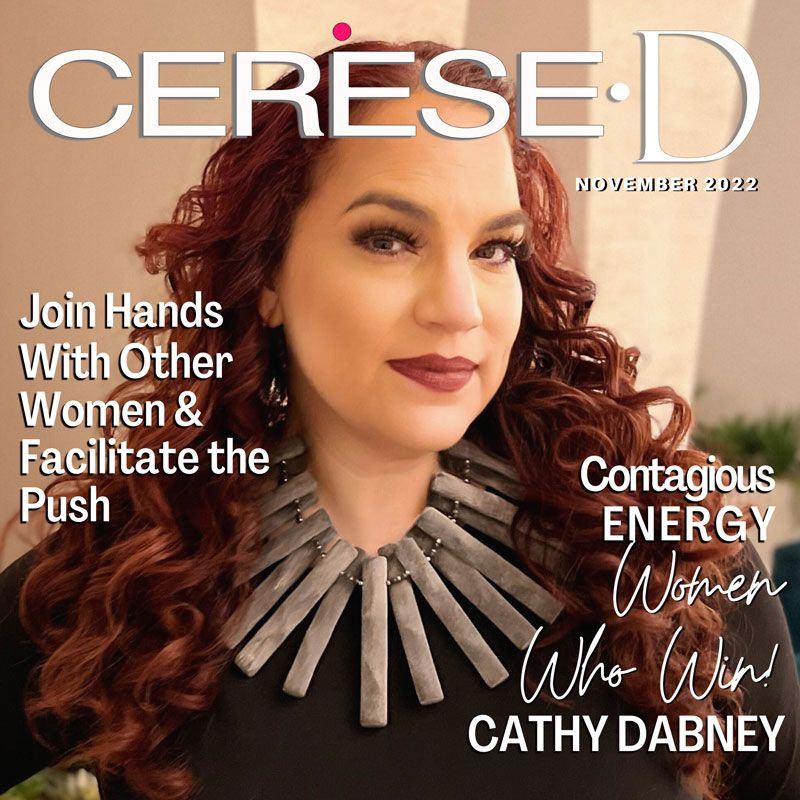 Woman with dark red lipstick and long auburn curly hair wearing a black top with a large silver colored necklace on a magazine cover