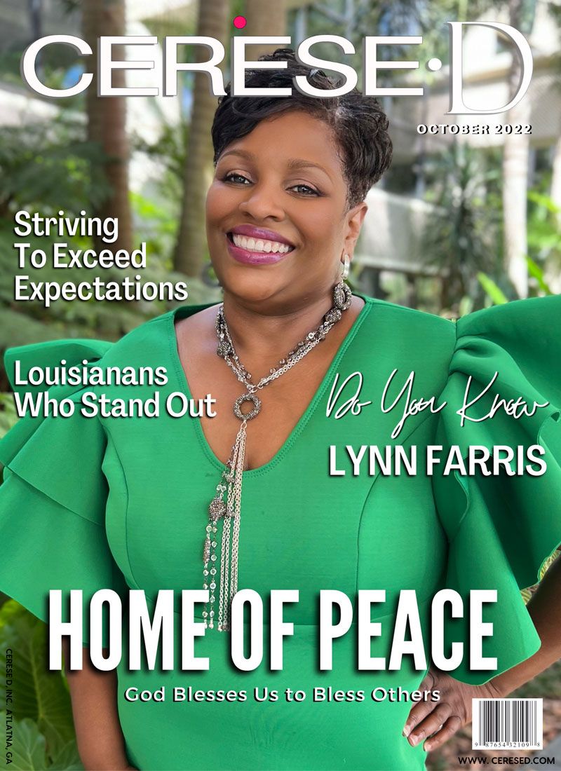 Smiling black woman wearing a bright green dress with large puffy sleeves and a large beaded silver necklace and large hoop earrings standing in a park setting.