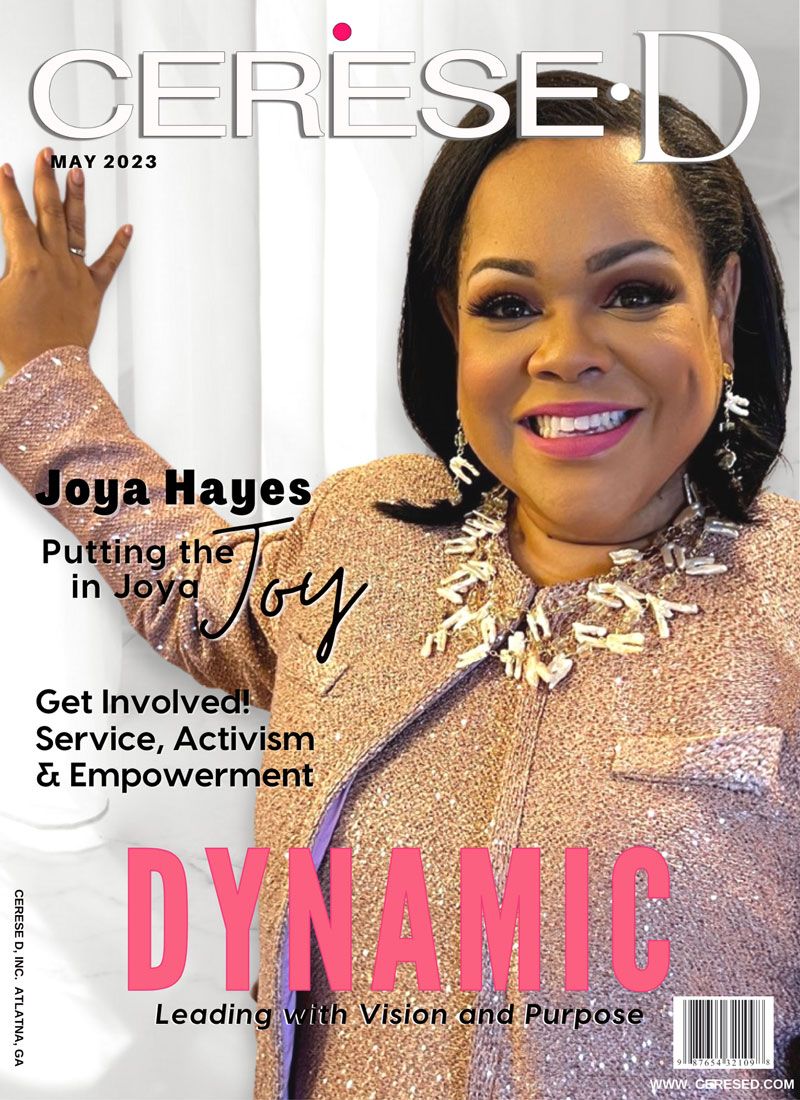 Smiling woman wearing a light brown top and leaning with one car against a wall with a large beaded necklace on a Cerese D magazine cover