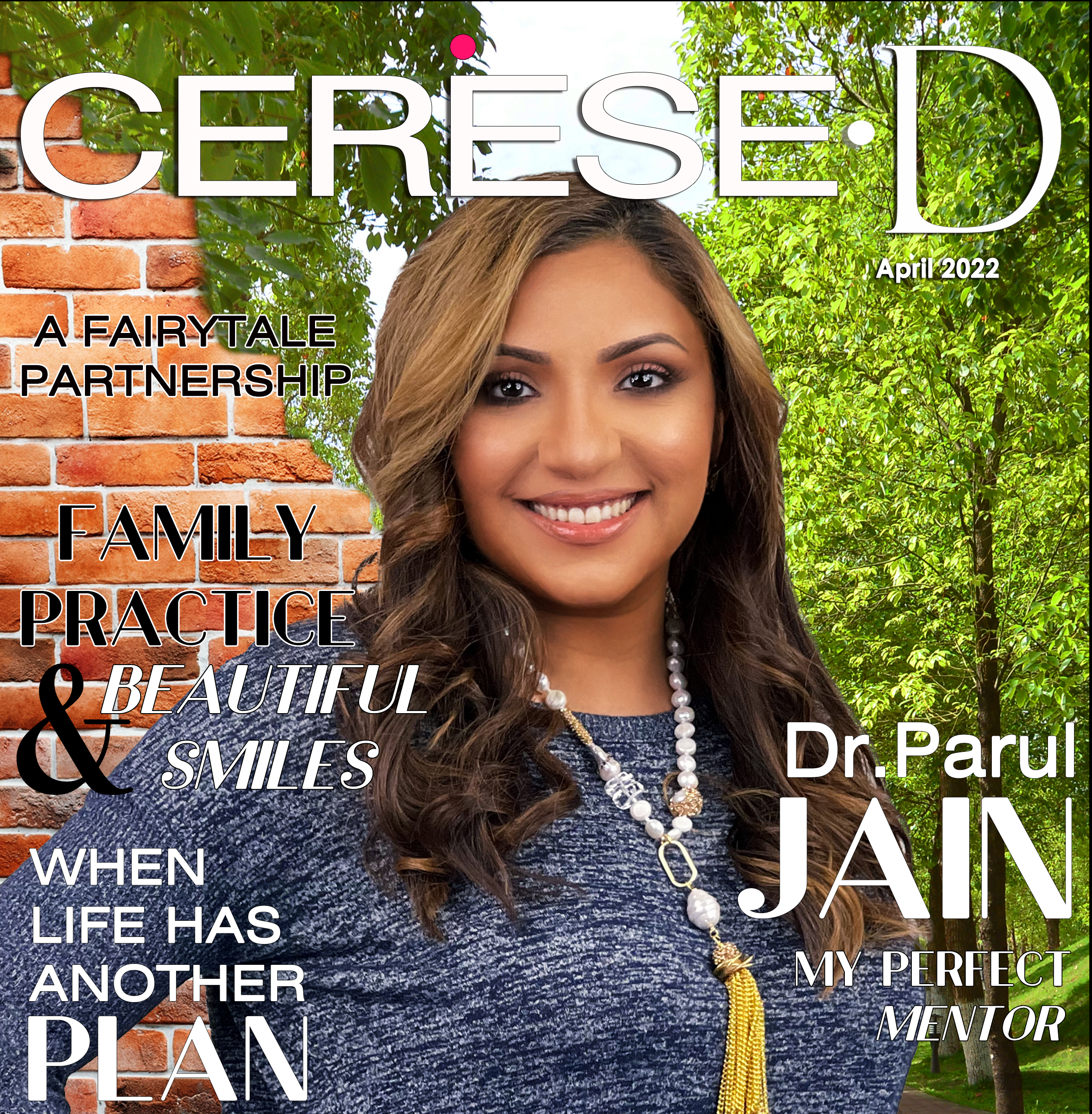 Dr Parul Jain in a blue top wearing a long tasseled necklace with trees and a brickwall in background