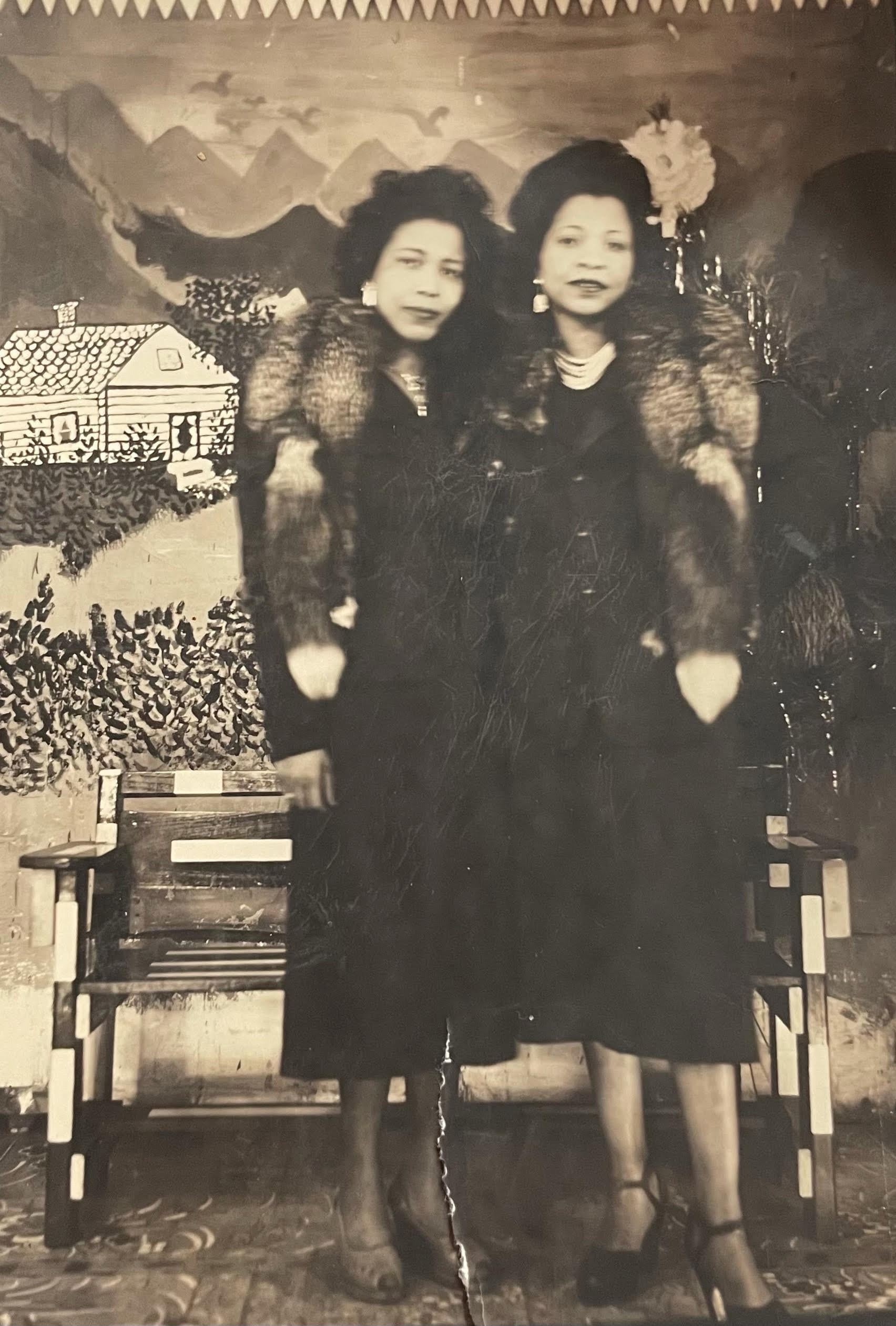 Two women dressed up in mink stoles and jewelry from the 1920s