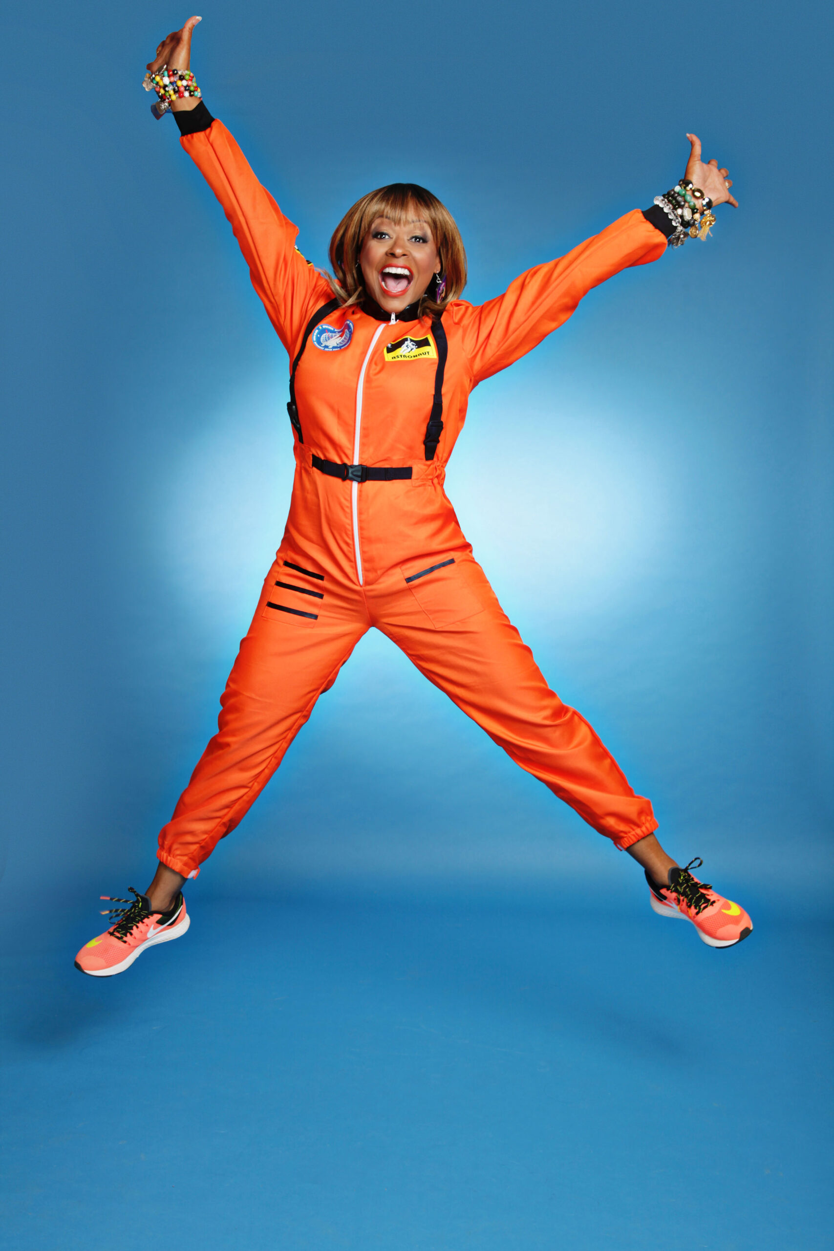 Sharon Caple Mcdougle jumping in orange flight suit