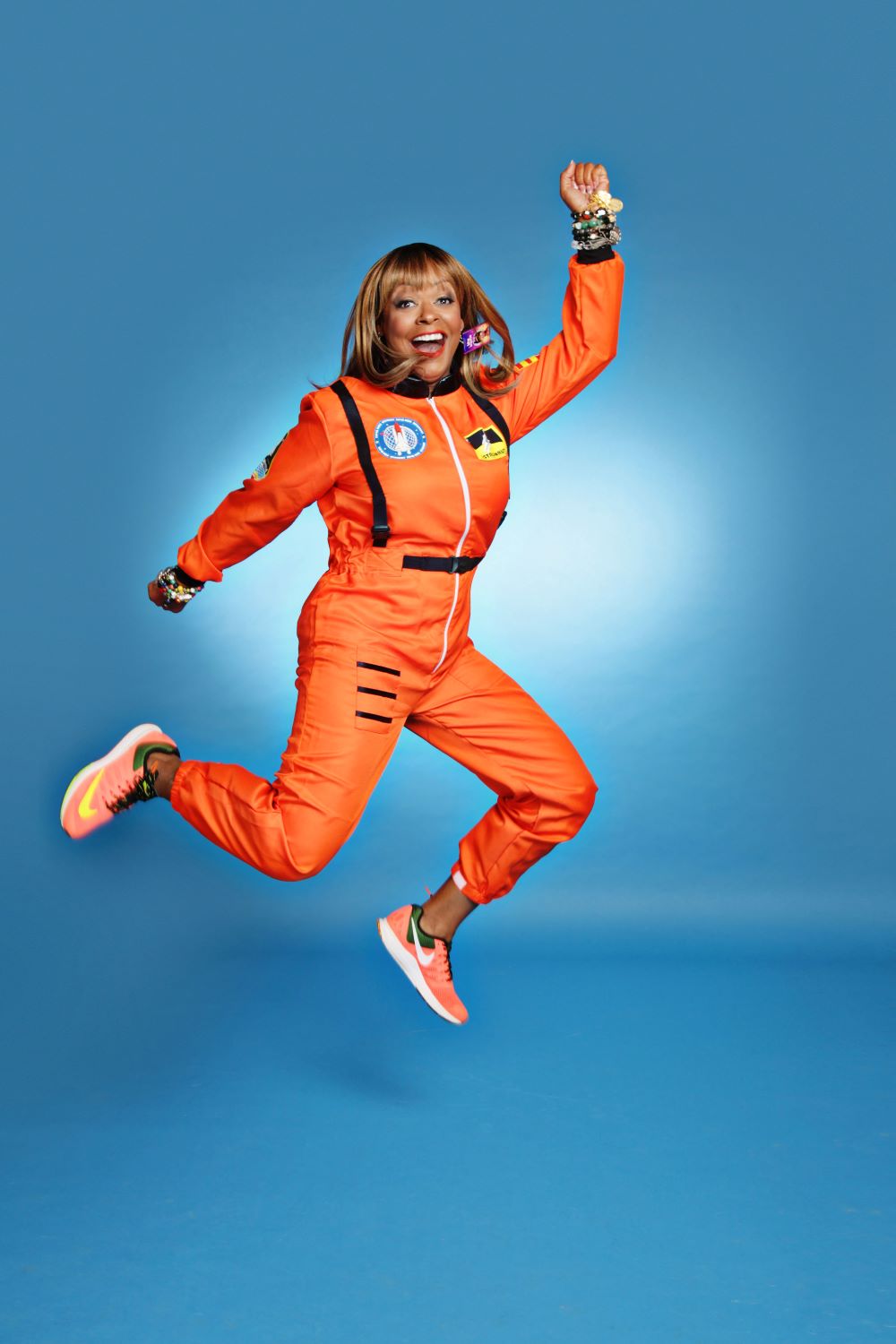 Sharon Caple Mcdougle jumping in orange flight suit